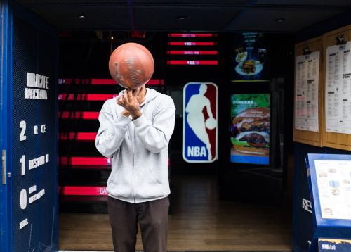 man holding basketball in front of NBA logo - nba healthcare fraud concept